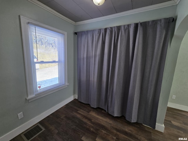 spare room featuring dark wood finished floors, baseboards, visible vents, and ornamental molding