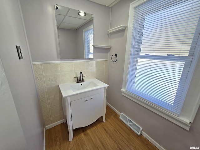 bathroom featuring vanity, wood finished floors, visible vents, a paneled ceiling, and tile walls