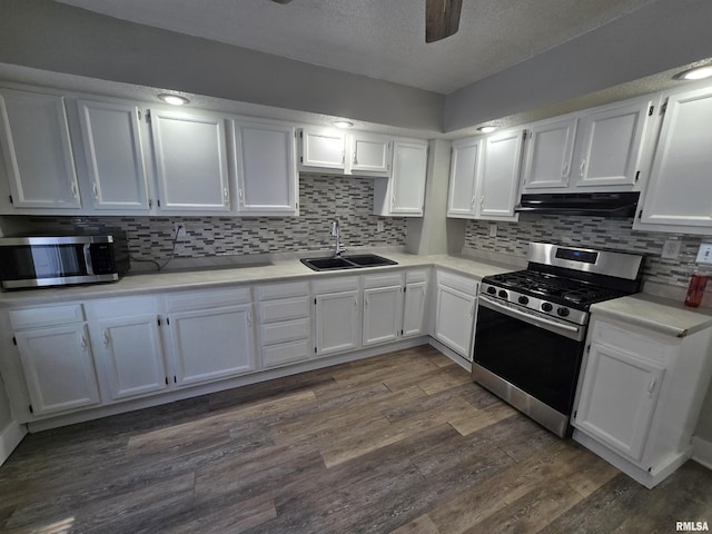 kitchen featuring a sink, under cabinet range hood, dark wood finished floors, white cabinetry, and stainless steel appliances