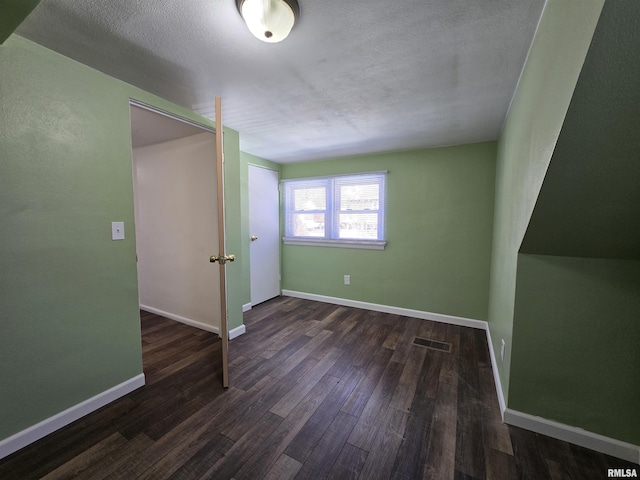 unfurnished bedroom with a textured ceiling, wood finished floors, visible vents, and baseboards