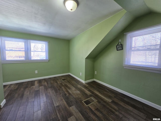 bonus room with visible vents, baseboards, lofted ceiling, and dark wood-style floors