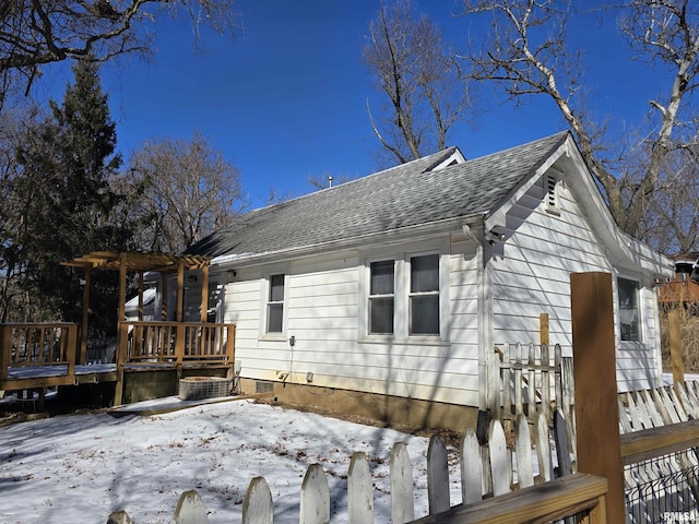 snow covered house featuring a pergola, roof with shingles, and a wooden deck