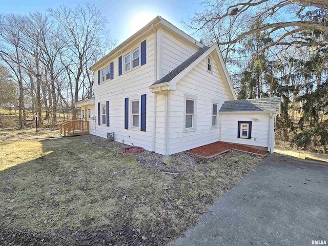 view of property exterior featuring a lawn and a shingled roof