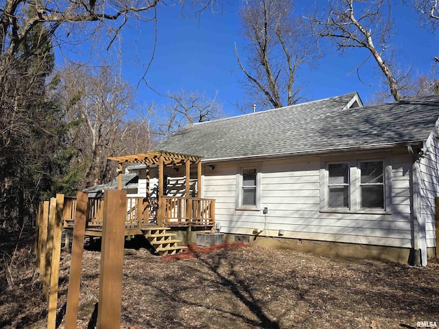 exterior space with a pergola, roof with shingles, and a wooden deck