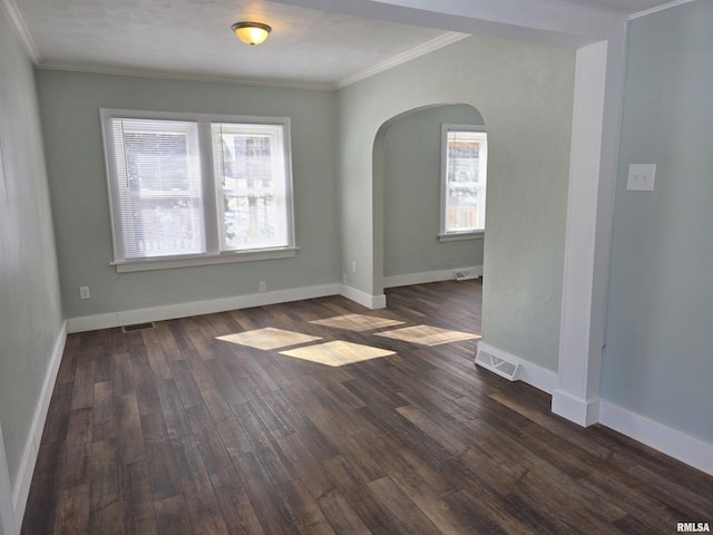 unfurnished room featuring arched walkways, visible vents, ornamental molding, and dark wood-style flooring