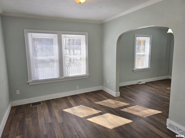 unfurnished room with visible vents, arched walkways, baseboards, and wood finished floors