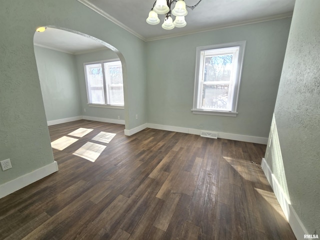 empty room featuring visible vents, ornamental molding, dark wood finished floors, arched walkways, and baseboards