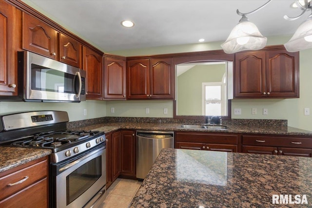 kitchen featuring decorative light fixtures, stainless steel appliances, recessed lighting, a sink, and dark stone counters