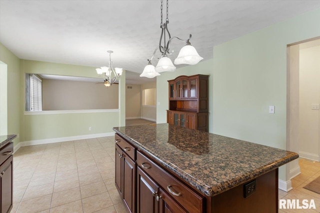 kitchen with light tile patterned floors, a kitchen island, baseboards, hanging light fixtures, and dark brown cabinets