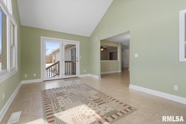 empty room featuring light tile patterned floors, baseboards, visible vents, and high vaulted ceiling