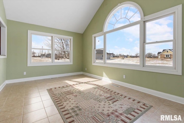 spare room featuring baseboards, visible vents, vaulted ceiling, and light tile patterned flooring