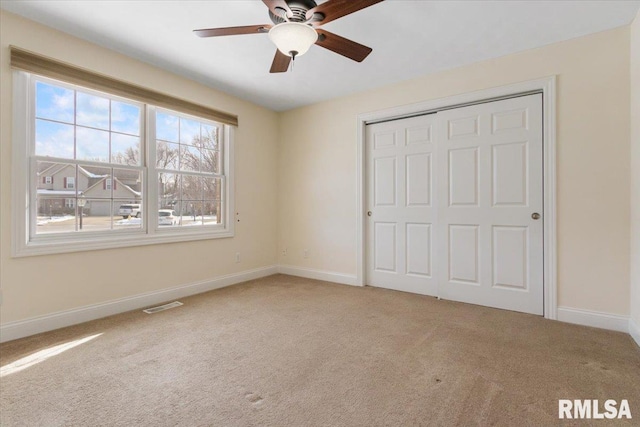 unfurnished bedroom featuring light carpet, baseboards, visible vents, and a closet