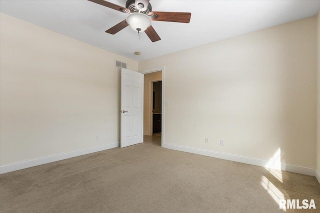 spare room featuring a ceiling fan, light colored carpet, visible vents, and baseboards