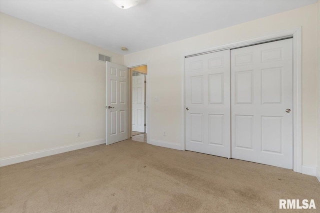 unfurnished bedroom with baseboards, a closet, visible vents, and light colored carpet