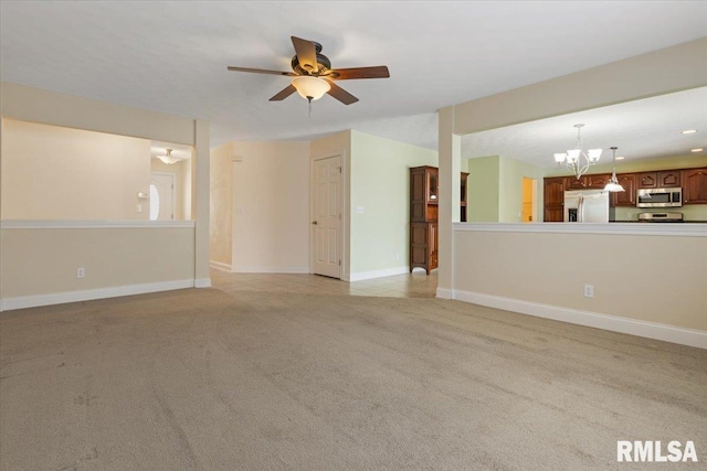 spare room featuring light colored carpet, baseboards, and ceiling fan with notable chandelier