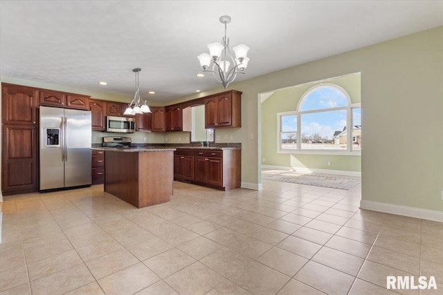 kitchen featuring pendant lighting, a kitchen island, appliances with stainless steel finishes, dark countertops, and an inviting chandelier