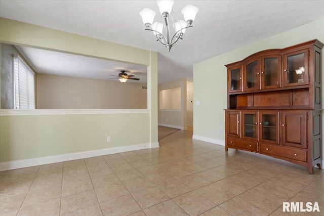 spare room featuring light tile patterned floors, baseboards, and ceiling fan with notable chandelier