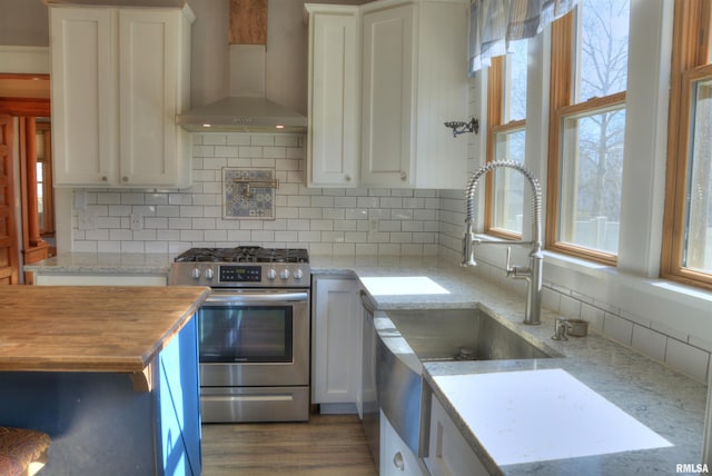 644 S Randolph St, Macomb, IL 61455 - kitchen featuring a wealth of natural light, gas stove, white cabinets, and wall chimney range hood