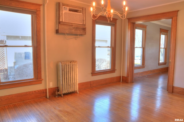 644 S Randolph St, Macomb, IL 61455 - empty room featuring a wall unit AC, radiator heating unit, ornamental molding, a chandelier, and light wood-type flooring