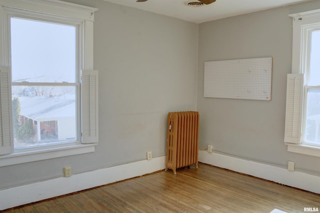 644 S Randolph St, Macomb, IL 61455 - empty room with plenty of natural light, radiator heating unit, a ceiling fan, and light wood-style floors