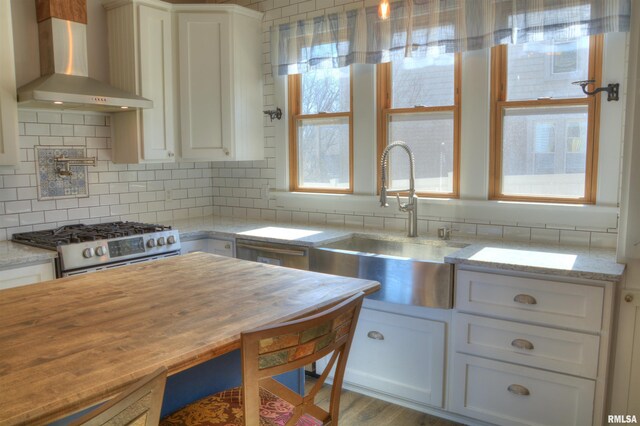 644 S Randolph St, Macomb, IL 61455 - kitchen with backsplash, gas stove, white cabinets, a sink, and wall chimney exhaust hood