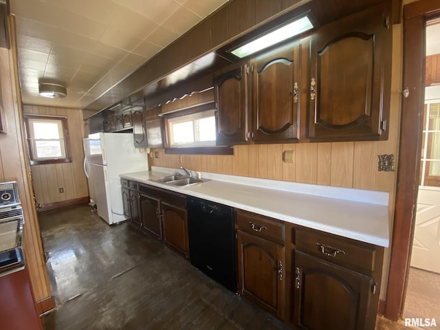 kitchen with wood walls, a sink, black dishwasher, light countertops, and freestanding refrigerator