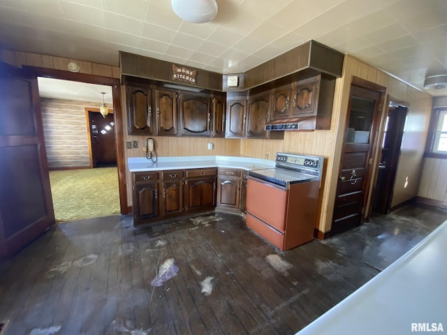 kitchen with wood walls, dark wood-style flooring, range, and dark brown cabinetry