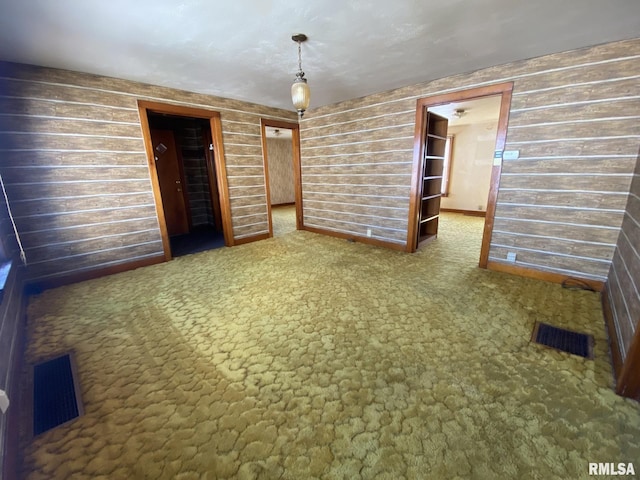 unfurnished bedroom with dark carpet, visible vents, and wooden walls