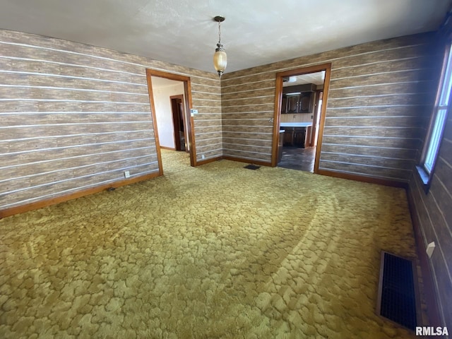 unfurnished dining area with visible vents, dark carpet, and wood walls