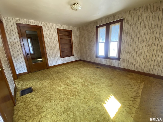 carpeted empty room with visible vents, baseboards, and wallpapered walls