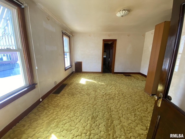 spare room featuring baseboards, visible vents, and light colored carpet