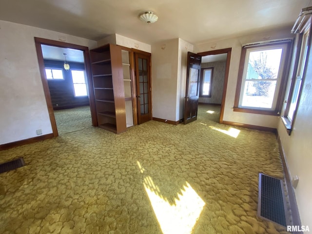 carpeted empty room featuring visible vents and baseboards