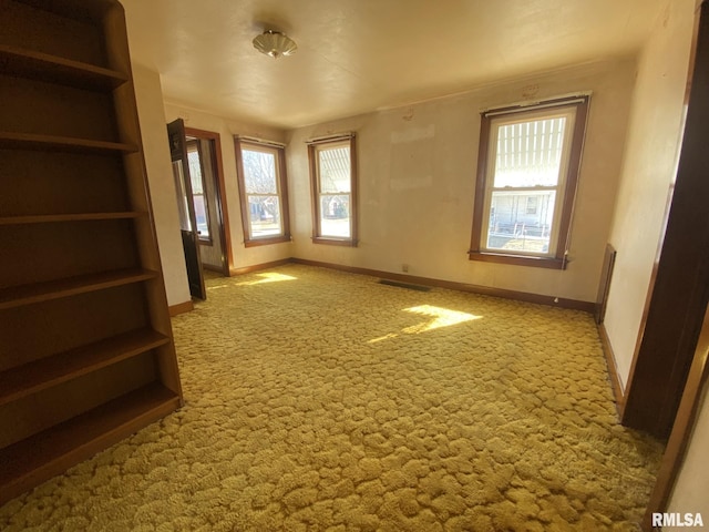 spare room with light colored carpet, visible vents, and baseboards