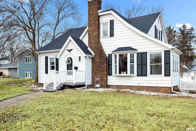 view of front of house featuring roof with shingles, a chimney, and a front lawn