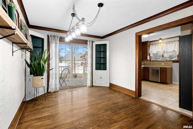 unfurnished dining area featuring light wood finished floors, baseboards, visible vents, and ornamental molding