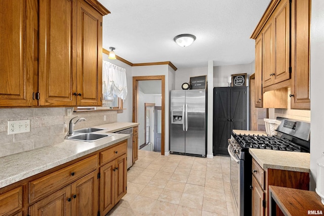 kitchen featuring brown cabinetry, appliances with stainless steel finishes, light countertops, and a sink