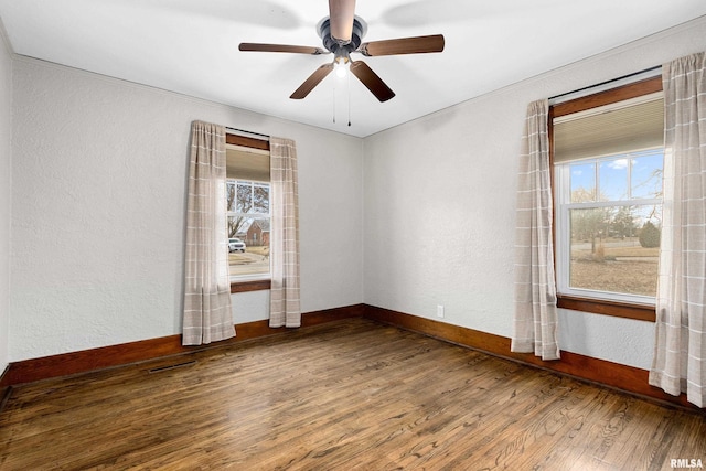 empty room with visible vents, baseboards, a textured wall, ceiling fan, and wood finished floors