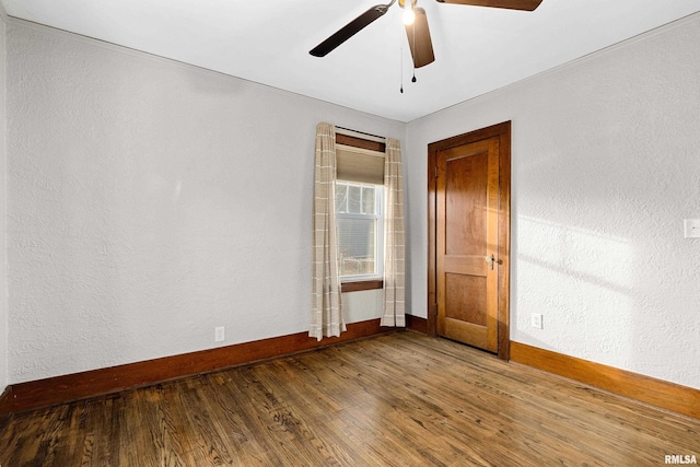 spare room with ceiling fan, a textured wall, wood finished floors, and baseboards