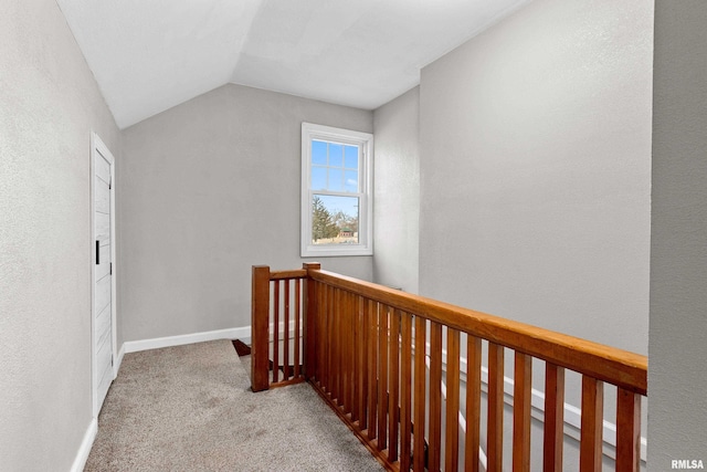 hallway featuring lofted ceiling, an upstairs landing, baseboards, and light colored carpet