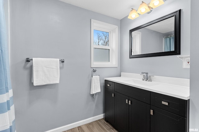 full bathroom featuring baseboards, wood finished floors, and vanity