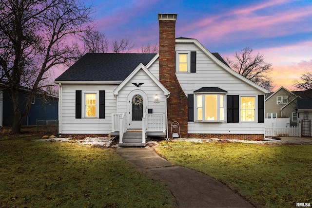 bungalow featuring a chimney, fence, a lawn, and roof with shingles