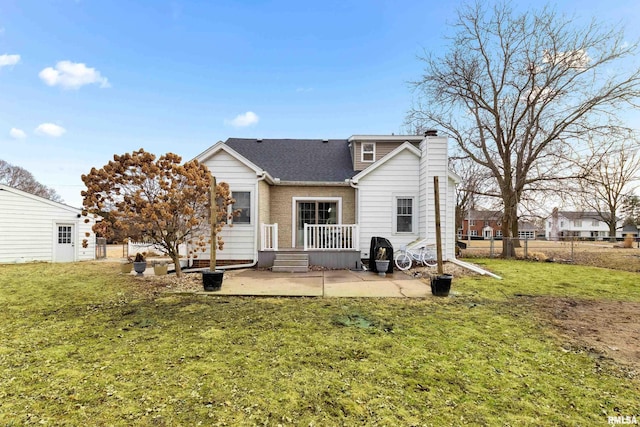 rear view of house with a patio, a lawn, a chimney, and fence