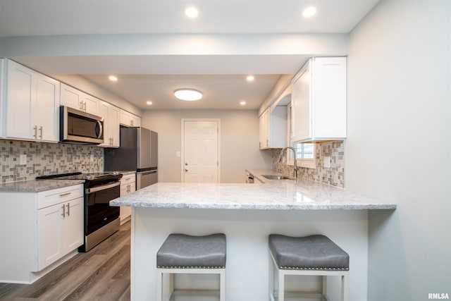 kitchen featuring a sink, appliances with stainless steel finishes, a kitchen bar, and white cabinets