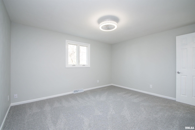 carpeted spare room with visible vents and baseboards