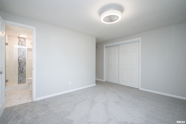 unfurnished bedroom featuring baseboards, ensuite bathroom, a closet, and light colored carpet