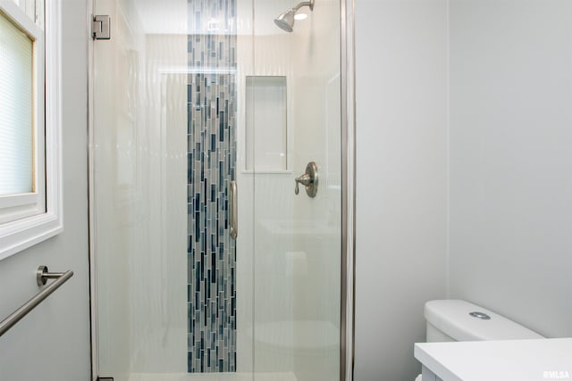 bathroom with a stall shower, vanity, and toilet