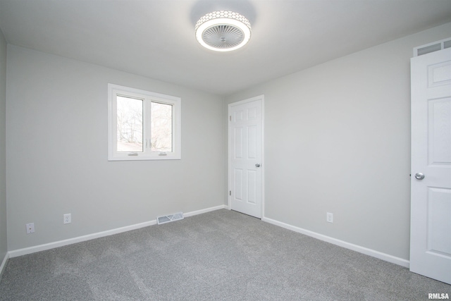 spare room featuring carpet flooring, visible vents, and baseboards