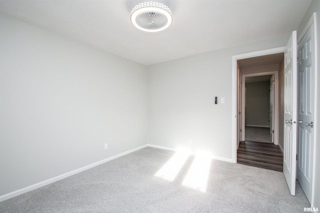 spare room with baseboards and light colored carpet