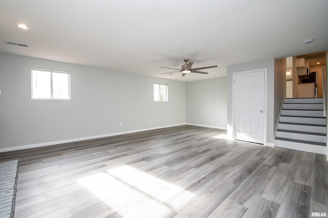 empty room featuring stairs, baseboards, a wealth of natural light, and light wood-style floors