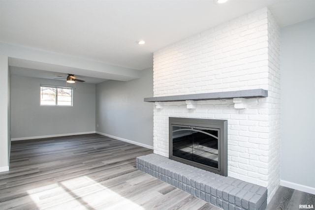 unfurnished living room featuring baseboards, a ceiling fan, wood finished floors, a brick fireplace, and recessed lighting